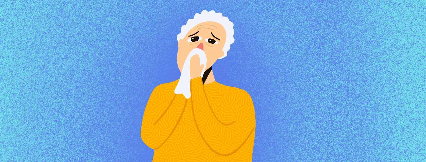 An elderly man with white hair blowing his nose into a tissue.