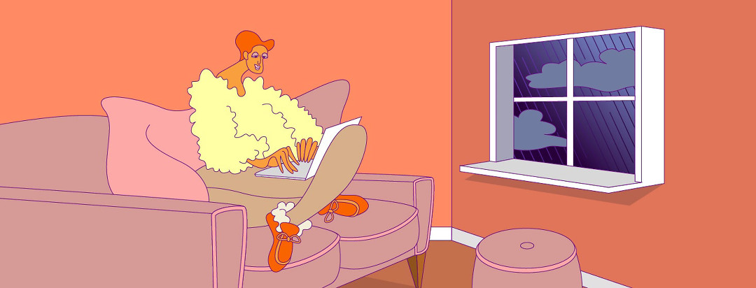 a woman in a furry sweater is cozy on the couch with her laptop in her autumnally colored warm home, as the window depicts dark dreary rain outside