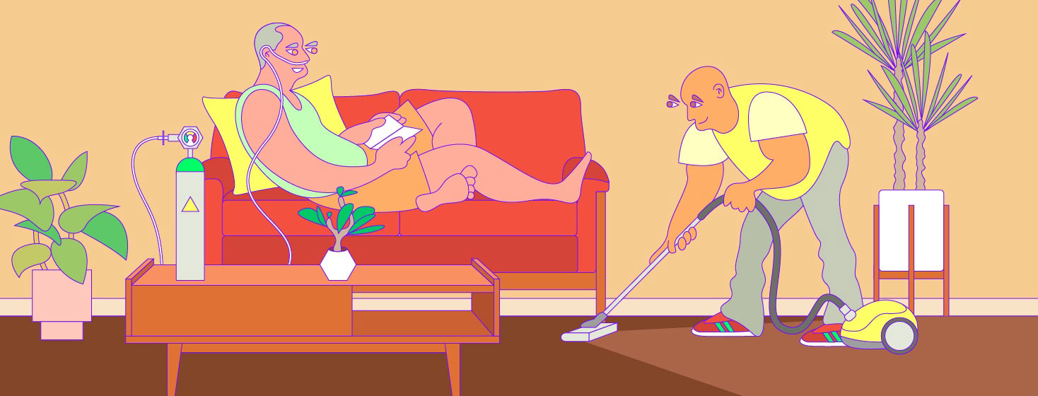 one man is relaxing on the sofa with oxygen as he accepts help from another man who is vacuuming for him.
