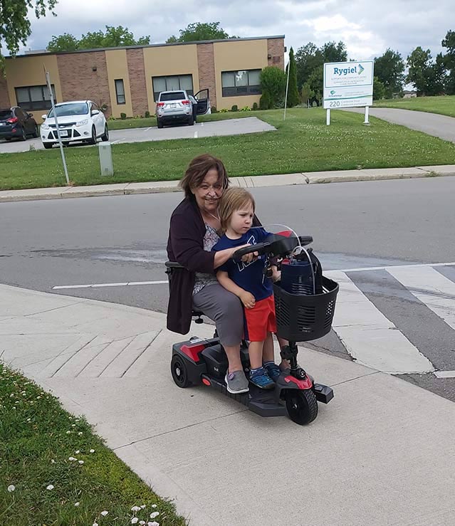 COPD Community Advocate Barbara Moore and her grandson on a motorized scooter.