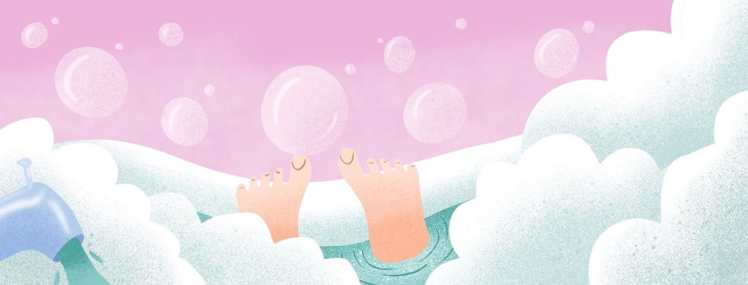 Feet resting on the edge of a bubble-filled bathtub.